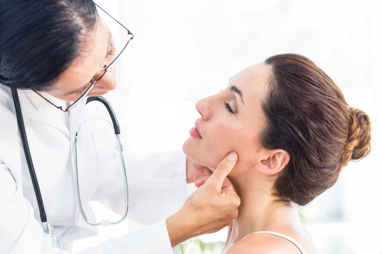 Doctor examining a patient's jaw to diagnose TMJ disorder at a pain clinic.